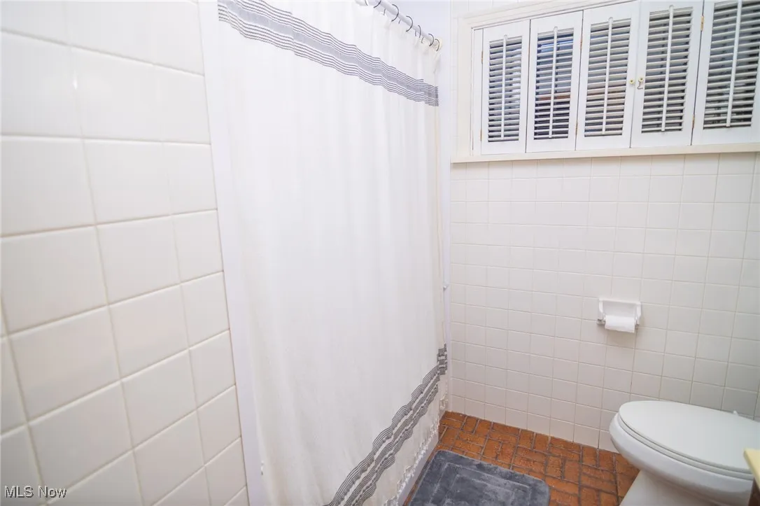 Full bath with tile walls and a shower with curtain
