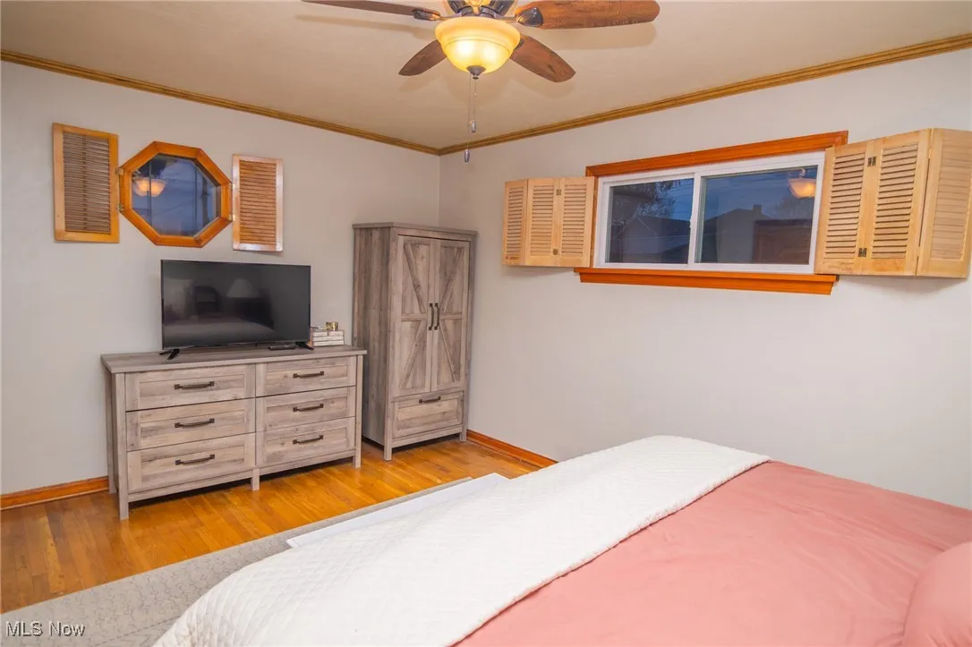 Bedroom featuring ornamental molding, light wood finished floors, and ceiling fan