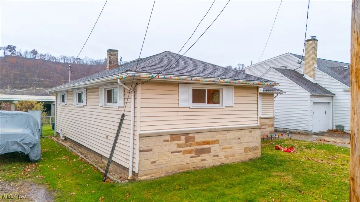 View of property exterior featuring a lawn, a shingled roof, and a chimney