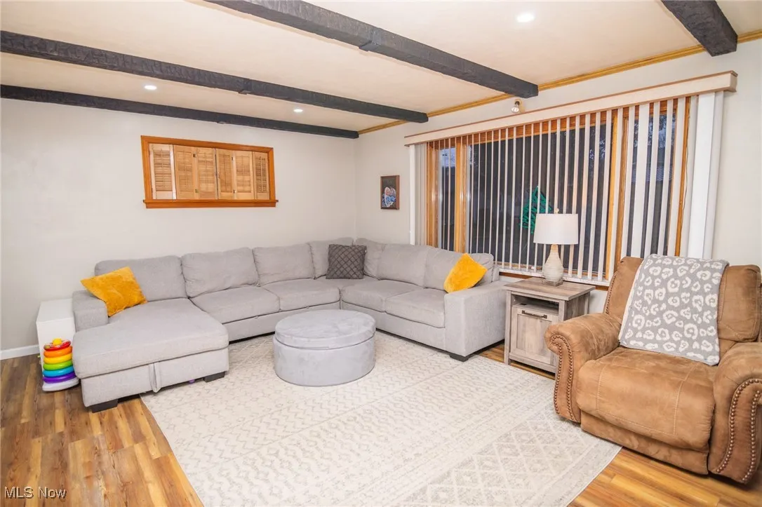 Living area with beamed ceiling, wood finished floors, and recessed lighting