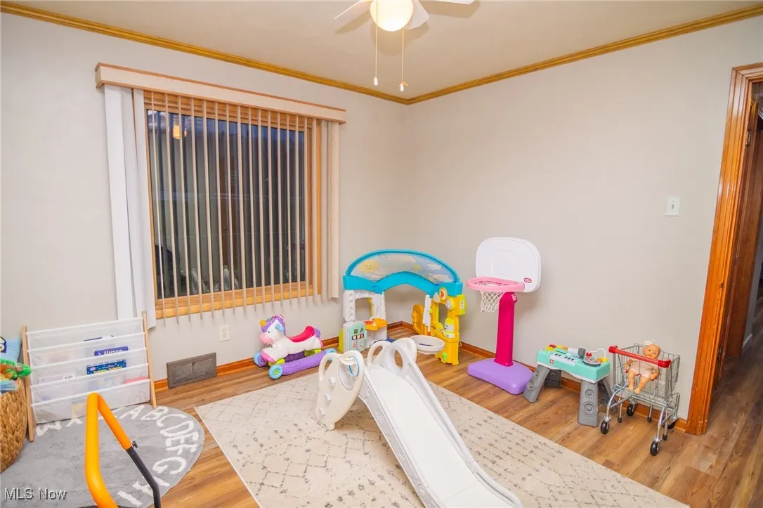Playroom with ornamental molding, light wood-style flooring, and a ceiling fan