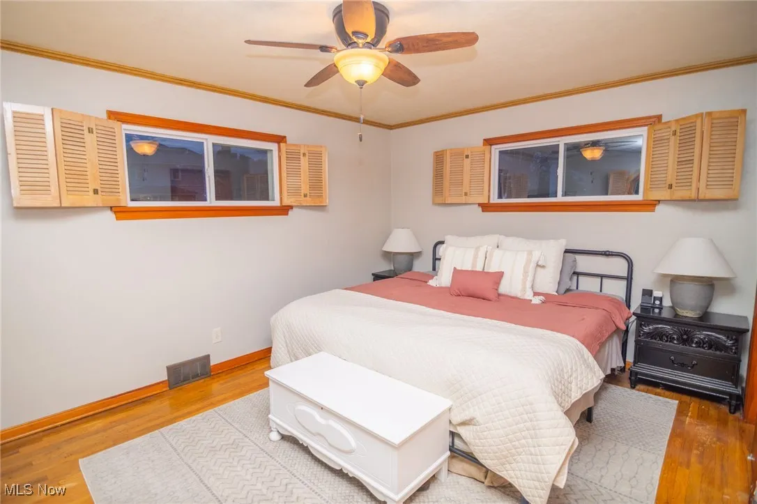 Bedroom featuring ornamental molding, wood finished floors, and ceiling fan