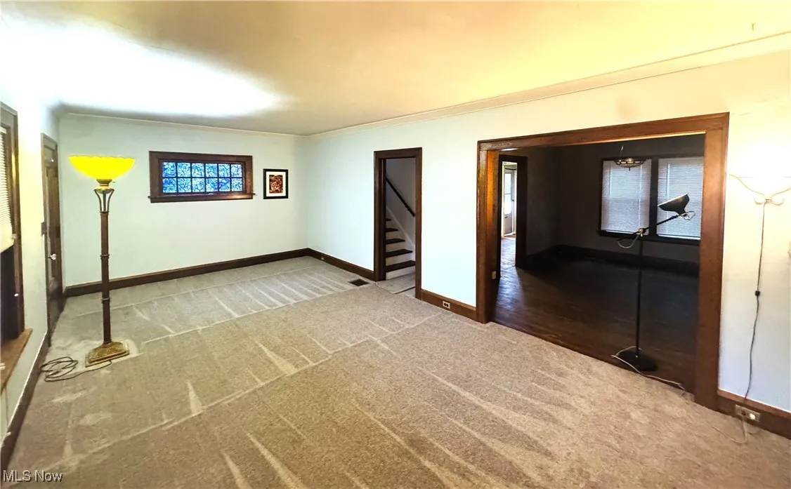 Unfurnished living room with carpet and ornamental molding