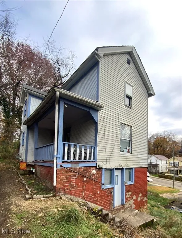 View of property exterior with brick siding and covered porch