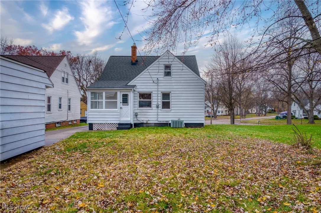 Back of property with a chimney, a shingled roof, and a yard