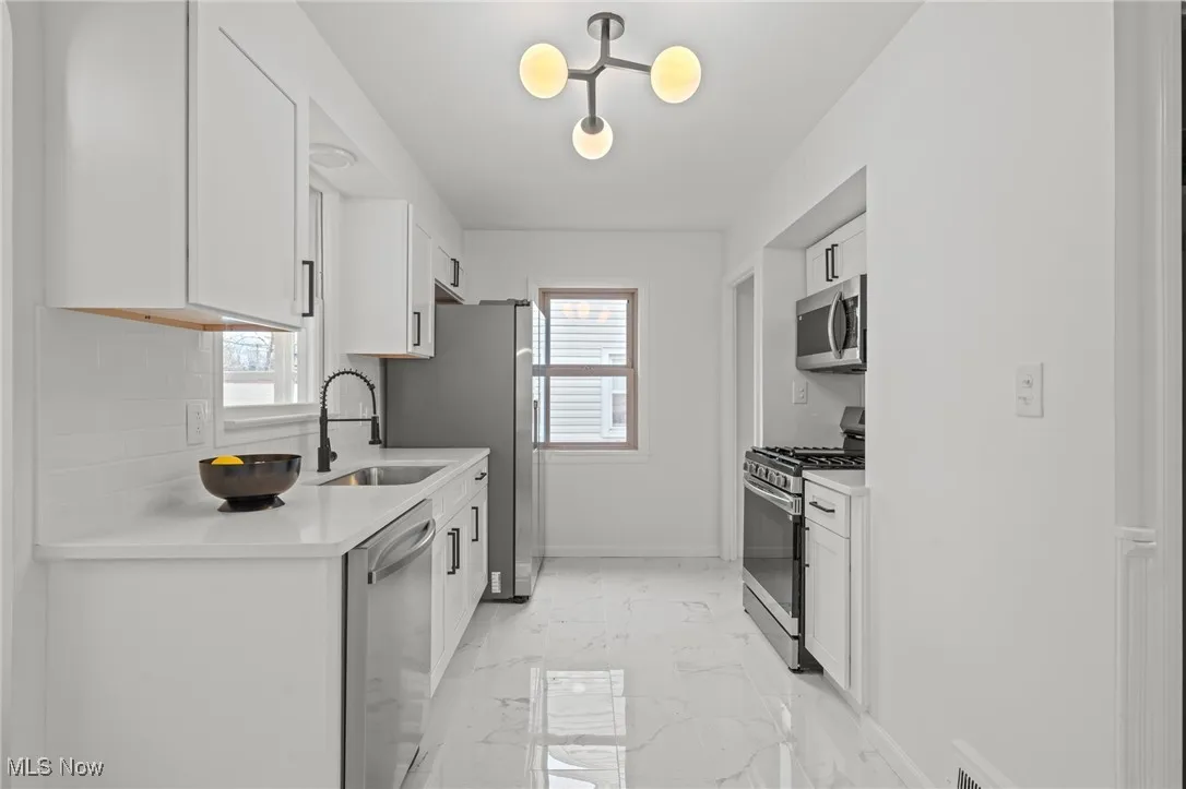 Kitchen with white cabinets, stainless steel appliances, and healthy amount of natural light