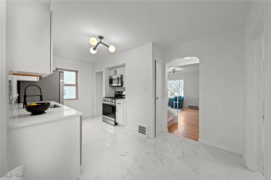 Kitchen with white cabinets, stainless steel appliances, healthy amount of natural light, and light stone counters