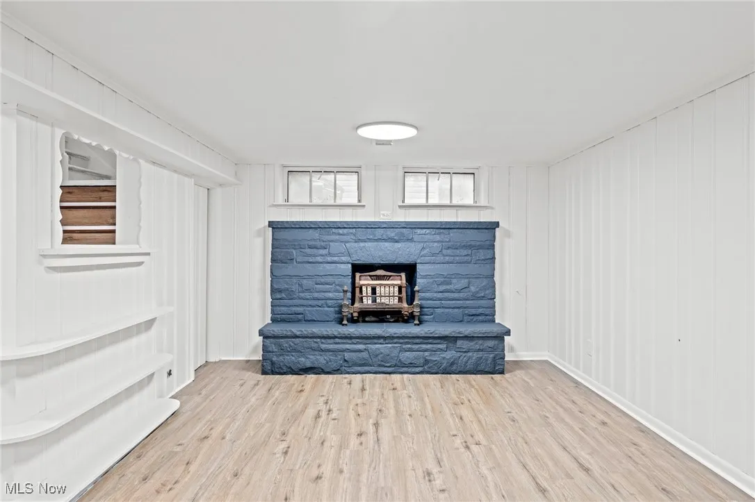 Unfurnished living room featuring wood finished floors and a stone fireplace