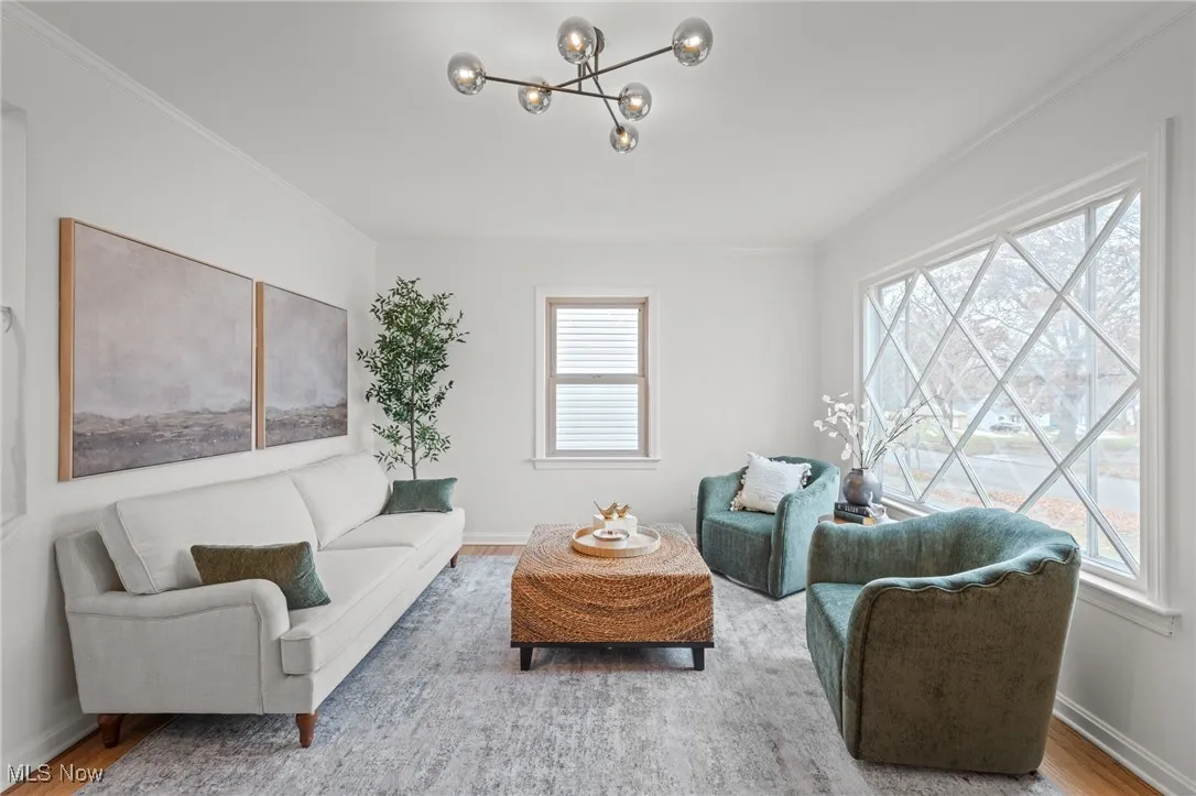Living area featuring plenty of natural light, ornamental molding, wood finished floors, and a chandelier