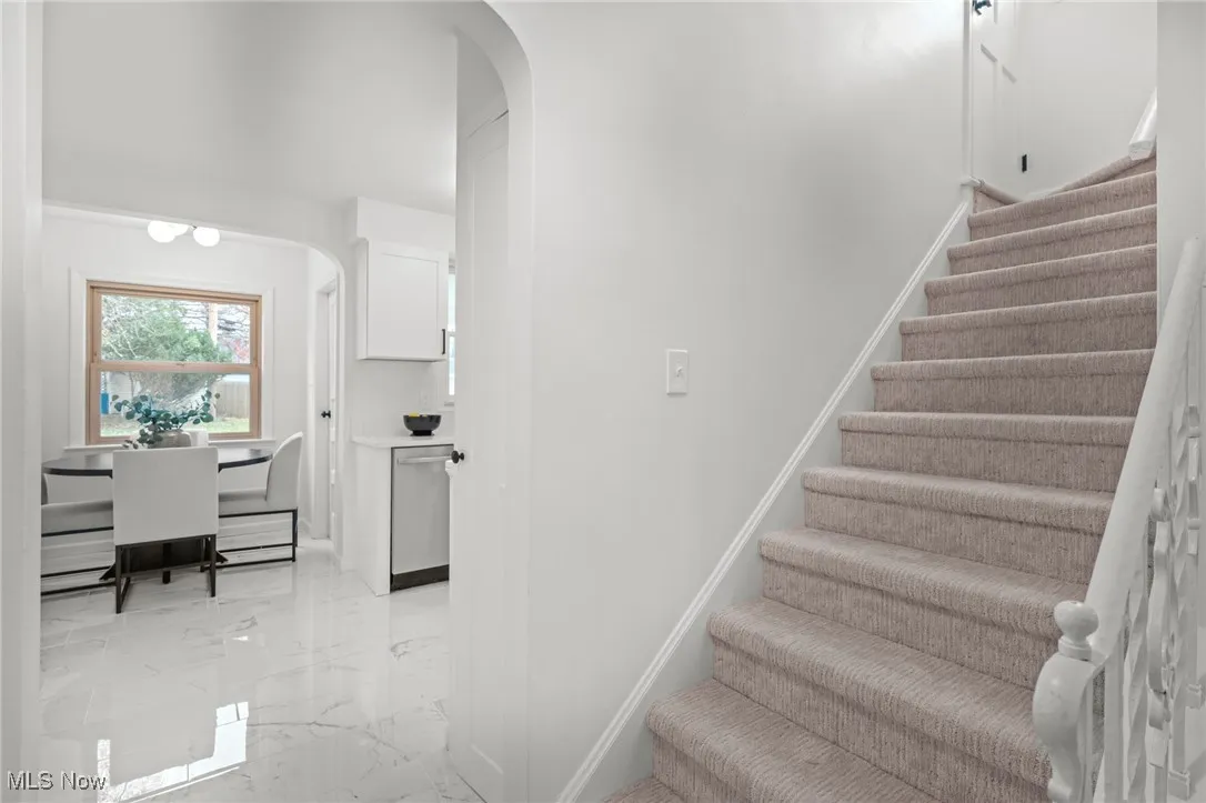 Staircase featuring arched walkways and marble tiled flooring
