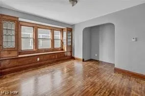 Spare room featuring arched walkways and wood finished floors