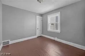 Empty room with baseboards and dark wood-style floors