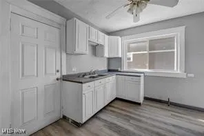 Kitchen with wood finished floors, white cabinets, and a ceiling fan