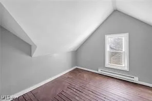 Additional living space with lofted ceiling, a baseboard radiator, and wood finished floors