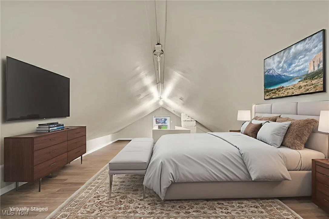 Bedroom with light wood-style flooring and lofted ceiling