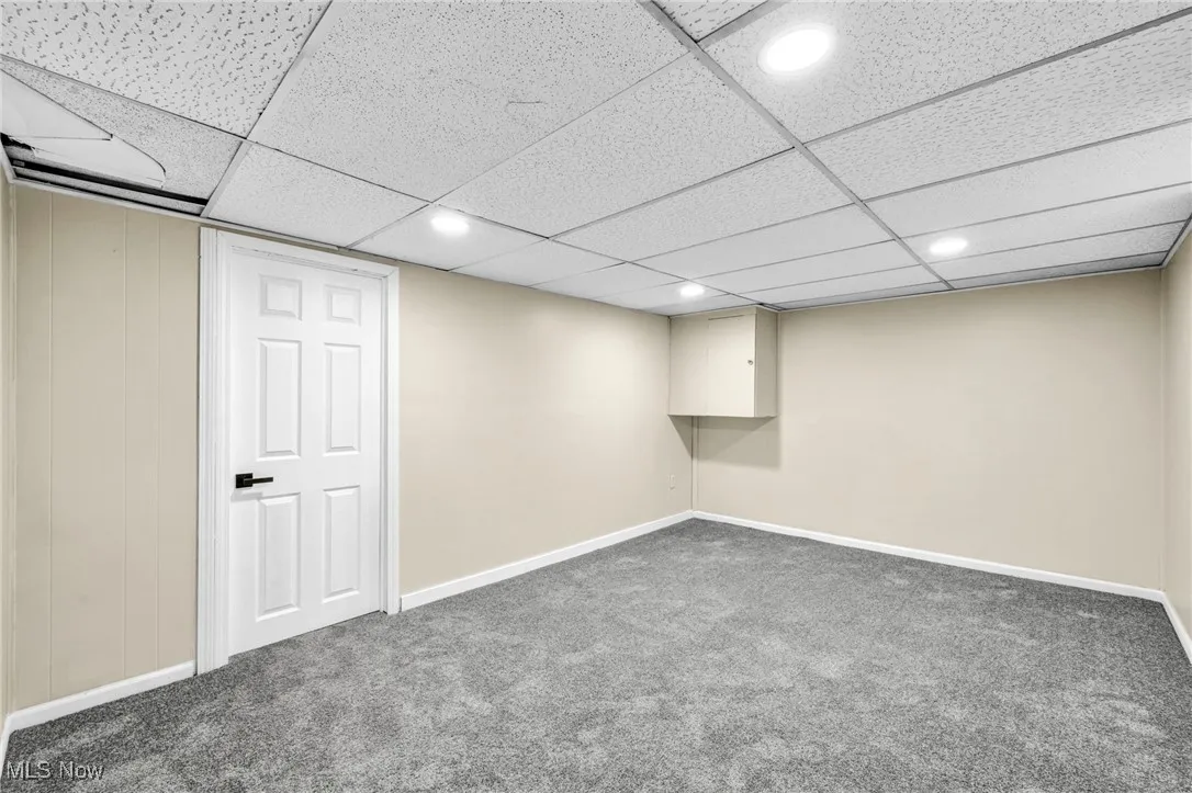 Finished below grade area with carpet flooring, recessed lighting, and a drop ceiling
