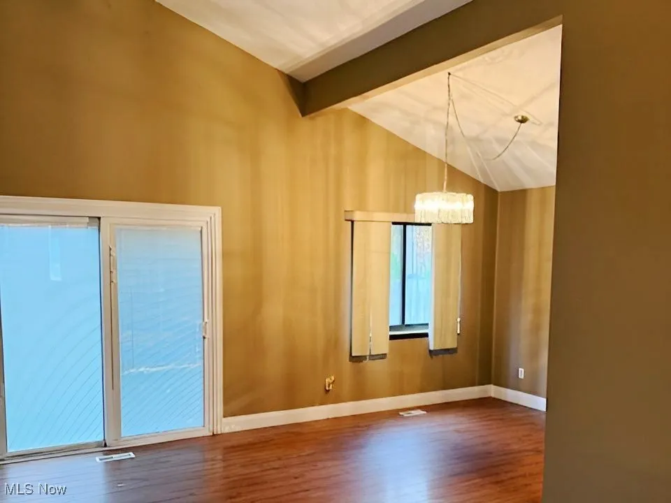 Spare room featuring wood finished floors and a chandelier