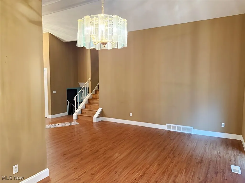 Unfurnished dining area with stairway, light wood-style flooring, and a chandelier