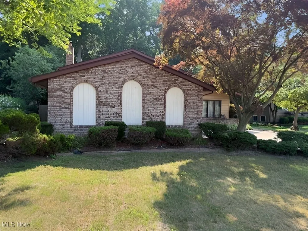 View of front of house with brick siding, a front yard, and a chimney