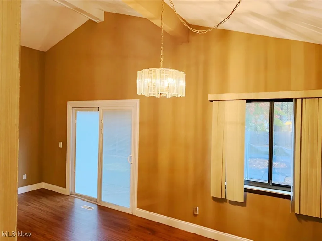 Unfurnished dining area featuring dark wood-style flooring and a chandelier