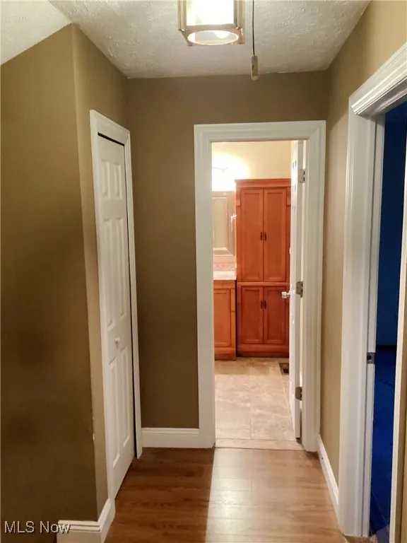 Hall with light wood finished floors and a textured ceiling
