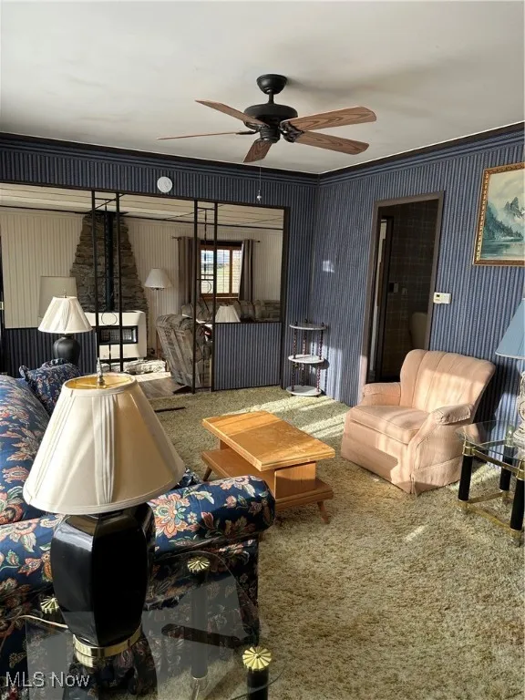 Living room featuring carpet floors, ceiling fan, and ornamental molding