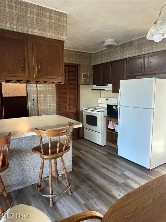 Kitchen featuring refrigerator, stove, Luxury Vinyl Flooring, light countertops, and Breakfast Bar with cabinets