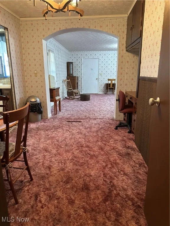 Dining area just off the kitchen and Bonus room with crown molding, arched walkways, carpet, a textured ceiling, and wallpapered walls
