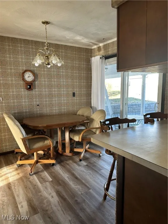 Dining room with LVF flooring, a chandelier, and ornamental molding and sliding door