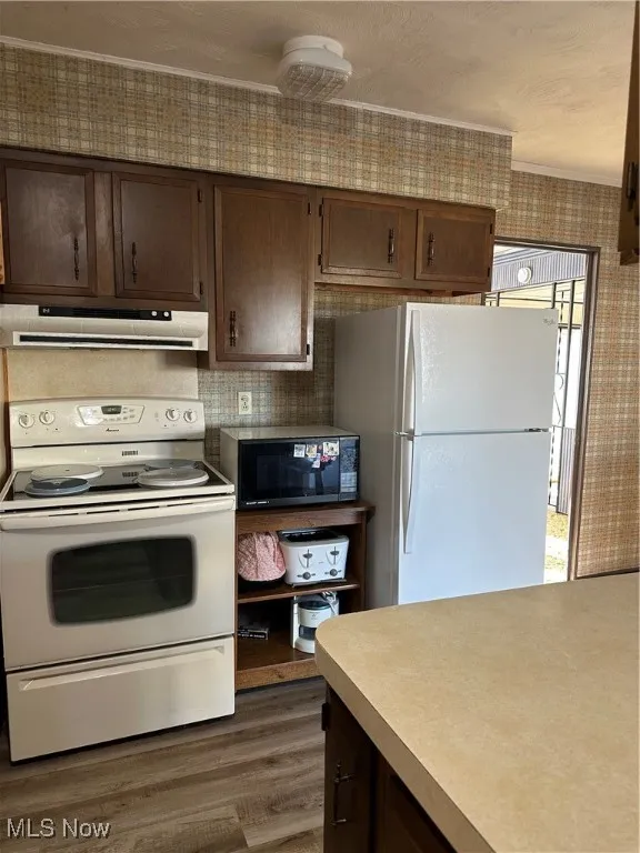 Kitchen with brown cabinetry, stove, white fridge, ventilation hood, electric range, and new Luxury Vinyl flooring