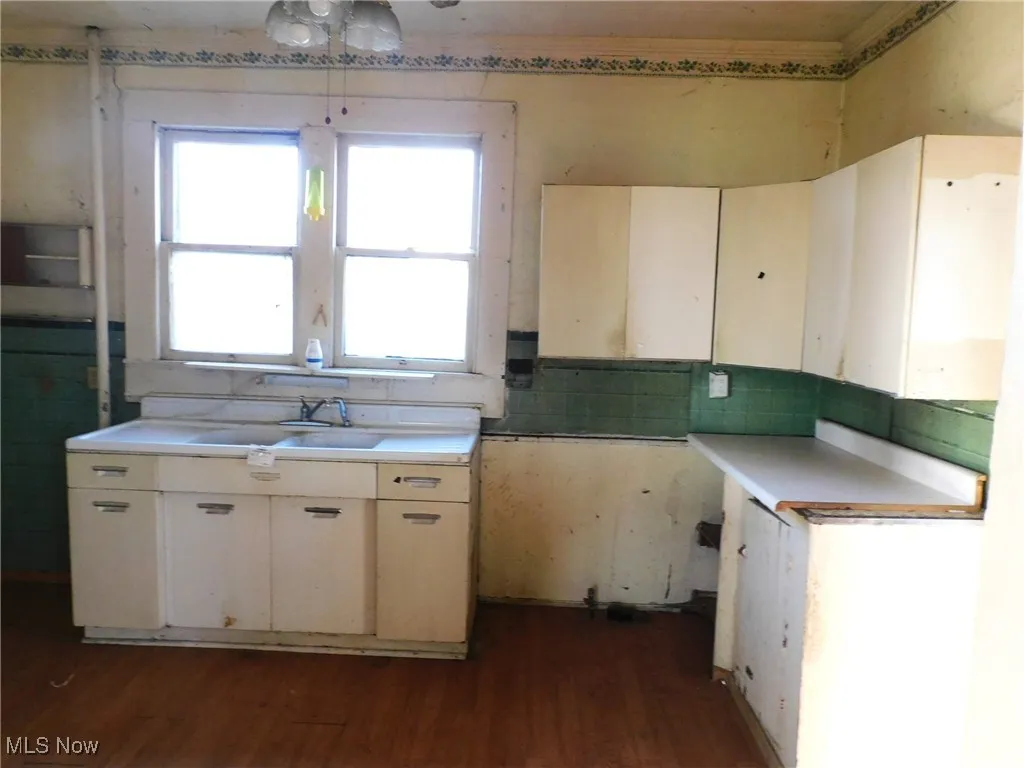 Kitchen view A featuring dark wood-style floors, light countertops, white cabinets, and decorative backsplash