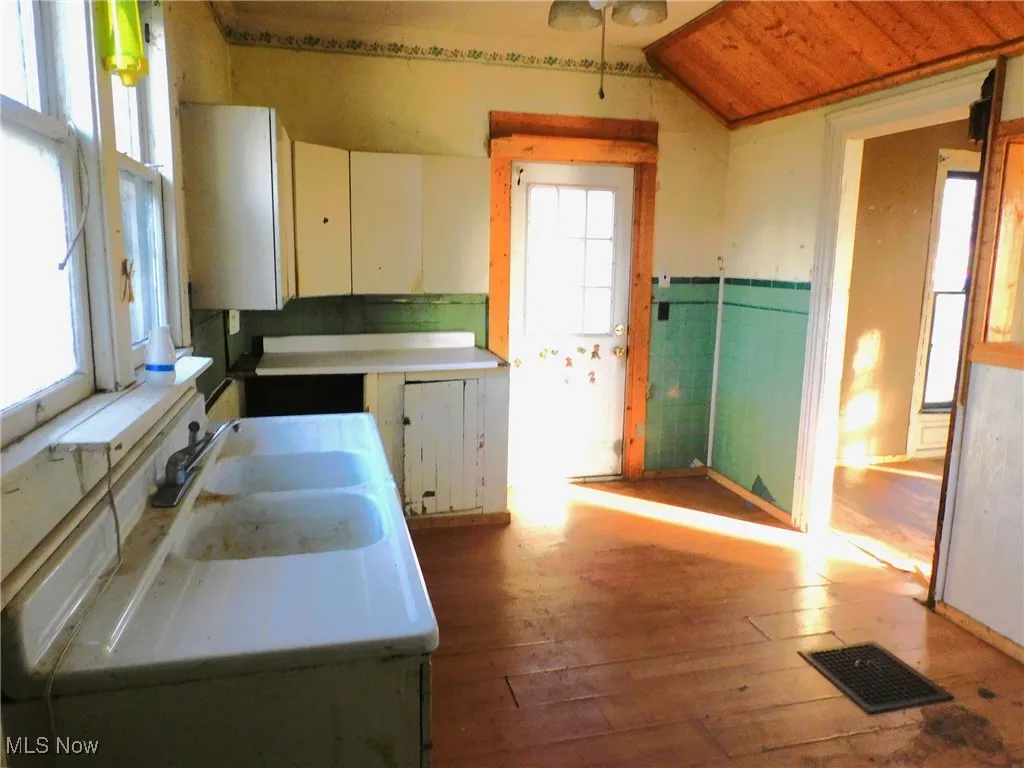 Kitchen B featuring light countertops, dark wood-style flooring, white cabinets, and wainscoting