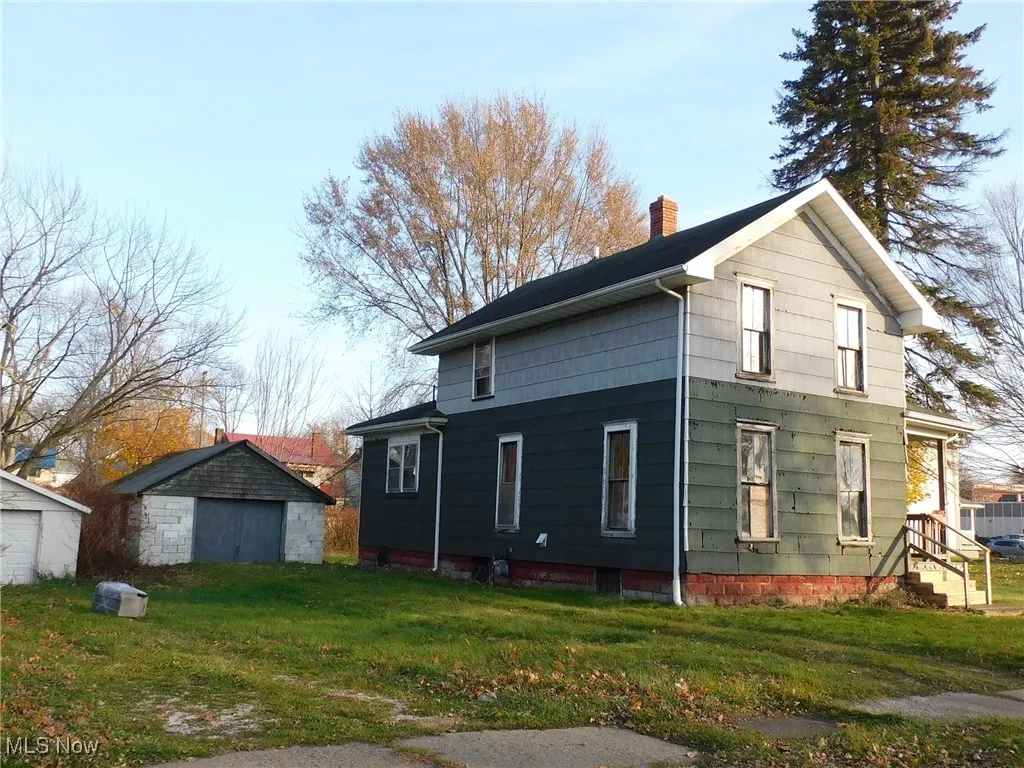 left View of side of property with a lawn, a chimney, and an outbuilding