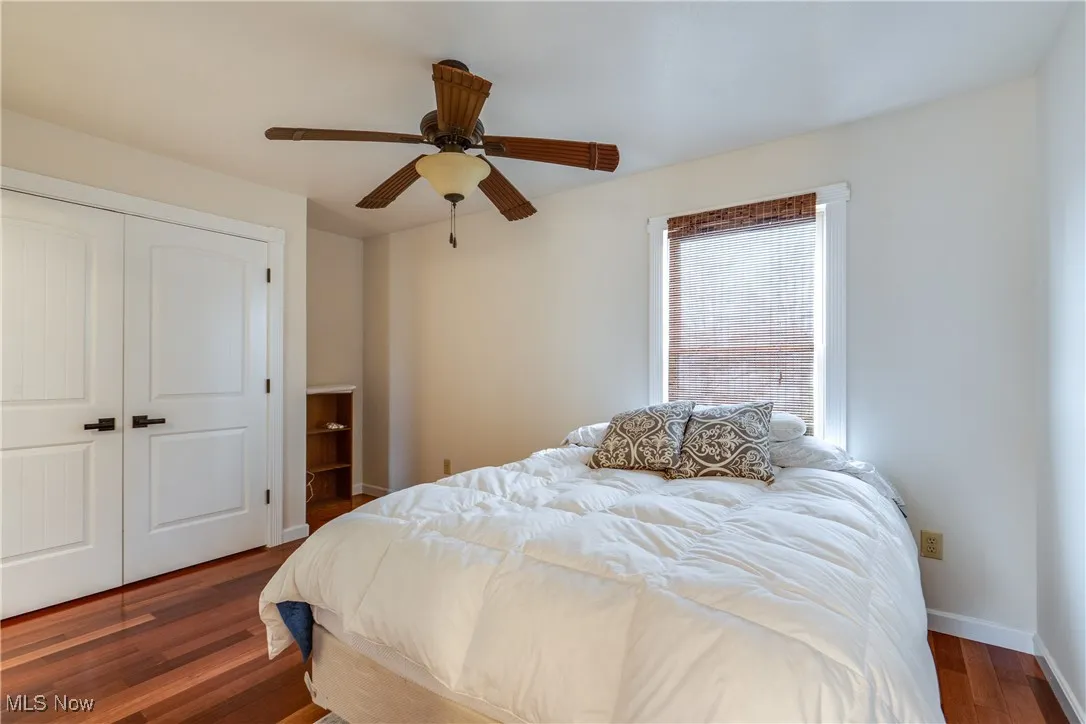 Bedroom with a closet, dark wood-type flooring, and a ceiling fan