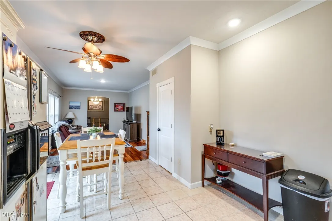 Dining room with crown molding, light tile patterned flooring, and a ceiling fan