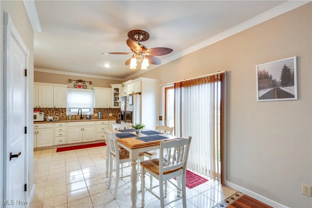 Dining space featuring ornamental molding, light tile patterned floors, plenty of natural light, and ceiling fan
