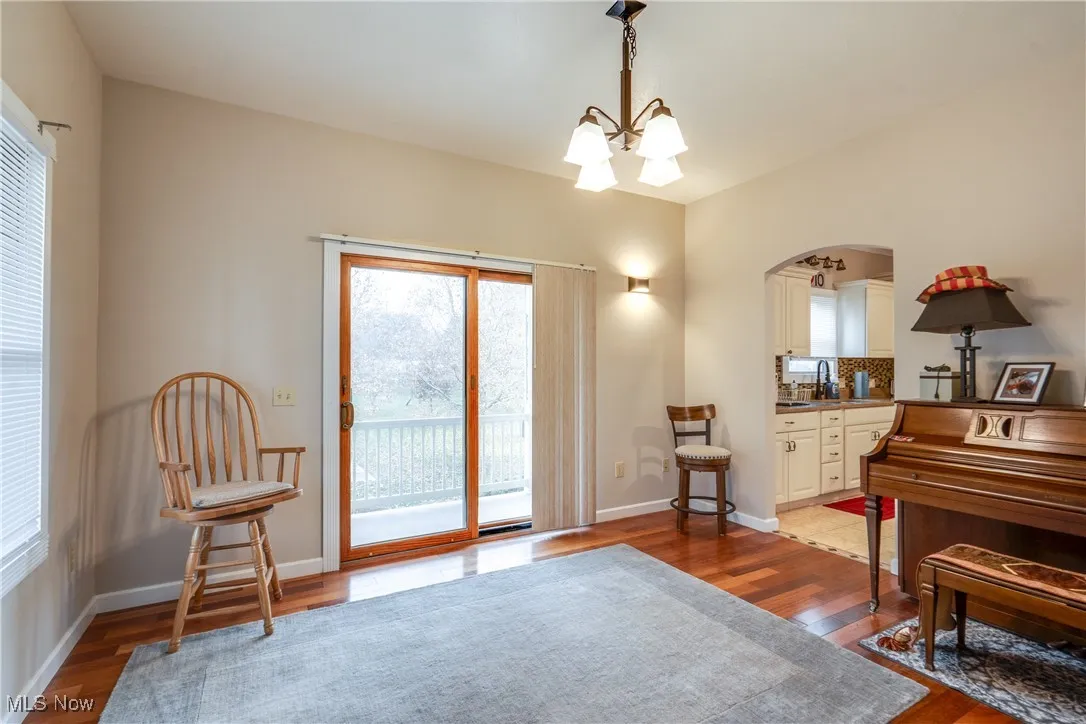 Living area featuring arched walkways, dark wood-style flooring, and a chandelier
