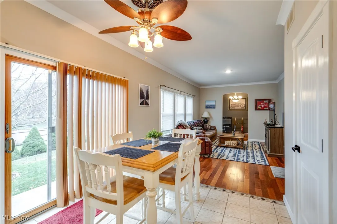 Dining area featuring light tile patterned floors, ceiling fan, crown molding, and a chandelier