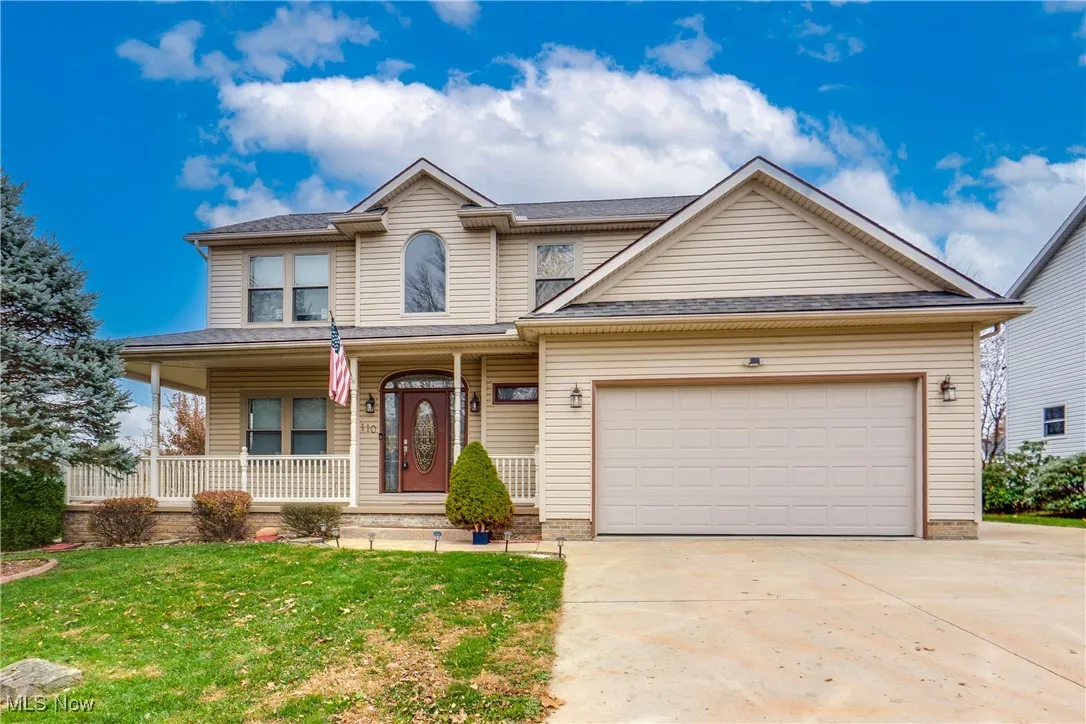 Traditional home with a porch, a front lawn, concrete driveway, and a garage