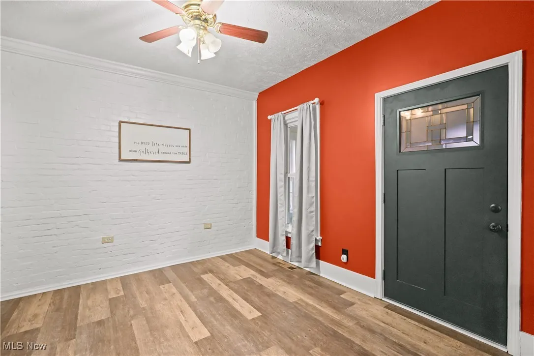 Entryway with brick wall, wood finished floors, a textured ceiling, and a ceiling fan