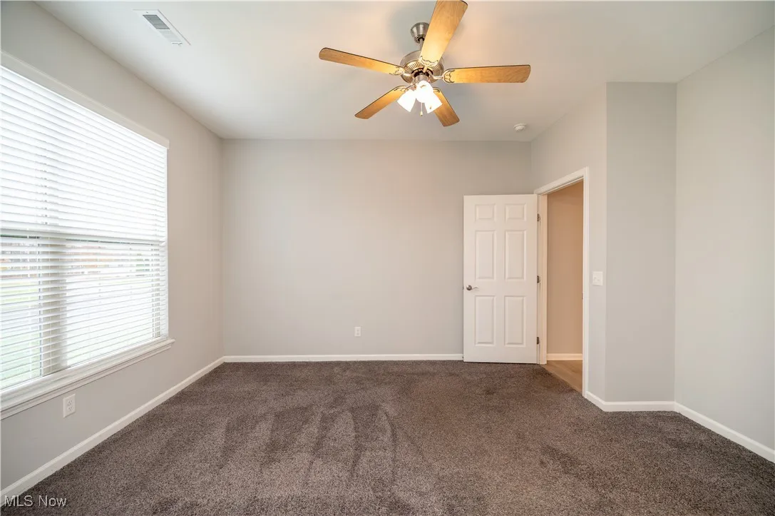 Second bedroom with ceiling fan and carpet