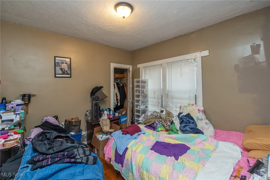 Bedroom featuring a textured ceiling, wood finished floors, and a closet
