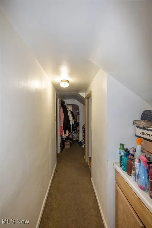 Corridor with dark colored carpet and baseboards
