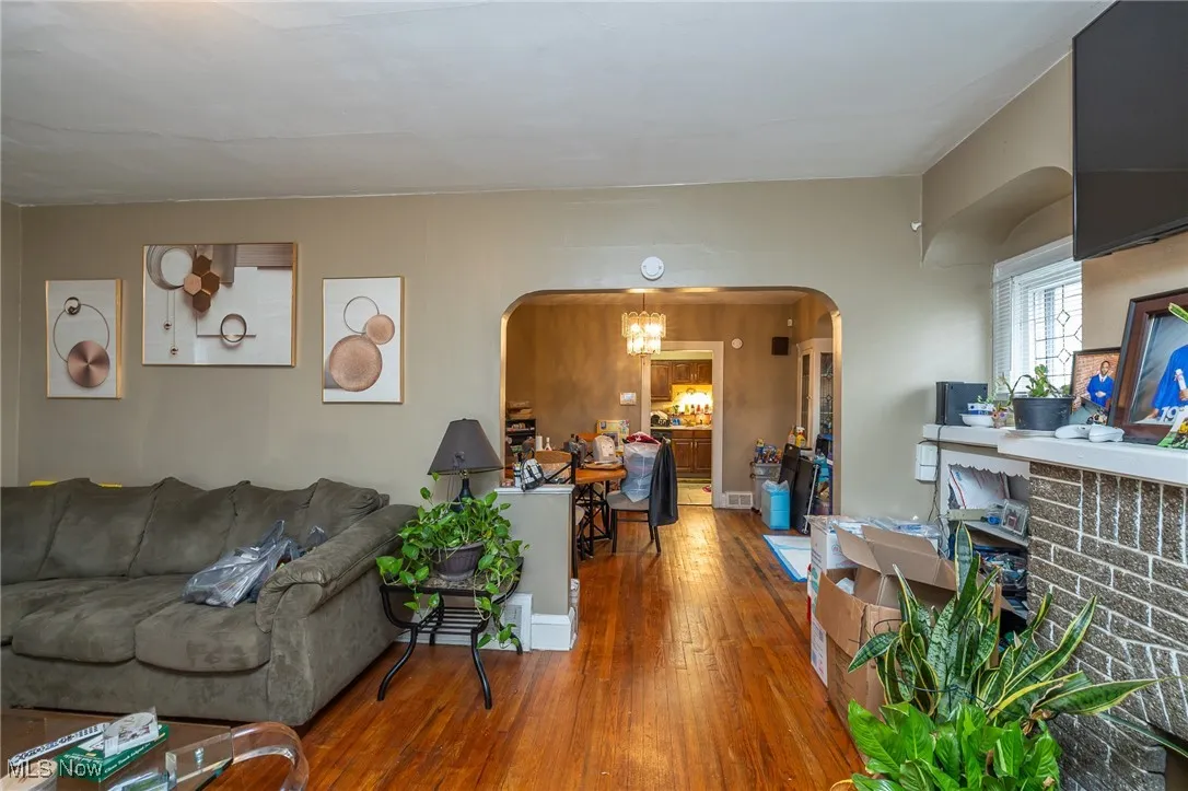Living room featuring arched walkways, a chandelier, and wood-type flooring