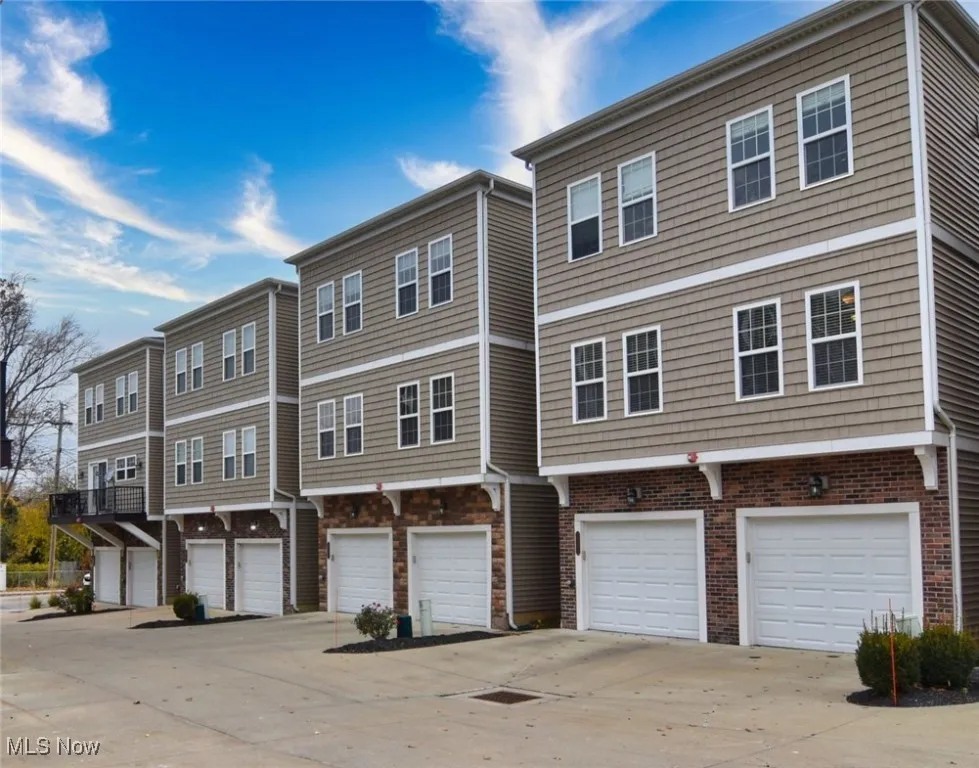 View of rear of home with a residential view, driveway, and a garage