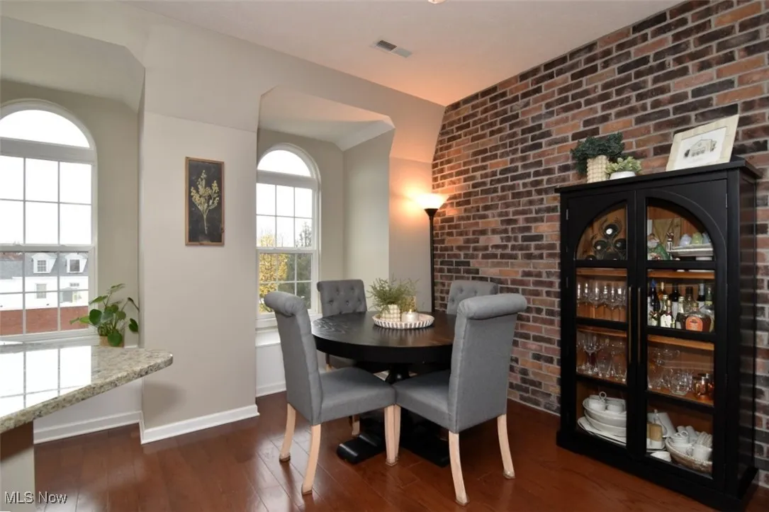 Dining room featuring brick wall and dark wood-type flooring