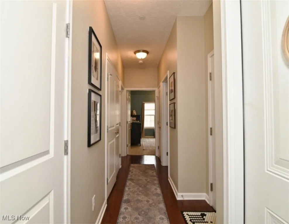 Hallway with dark wood-type flooring and a textured ceiling