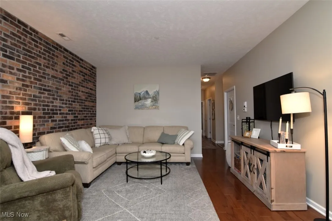 Living area with wood finished floors, a textured ceiling, and brick wall