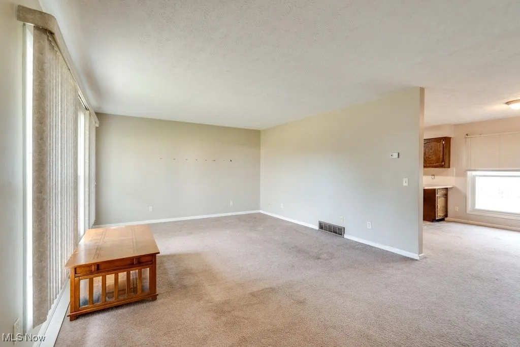 Unfurnished room with light carpet and a textured ceiling