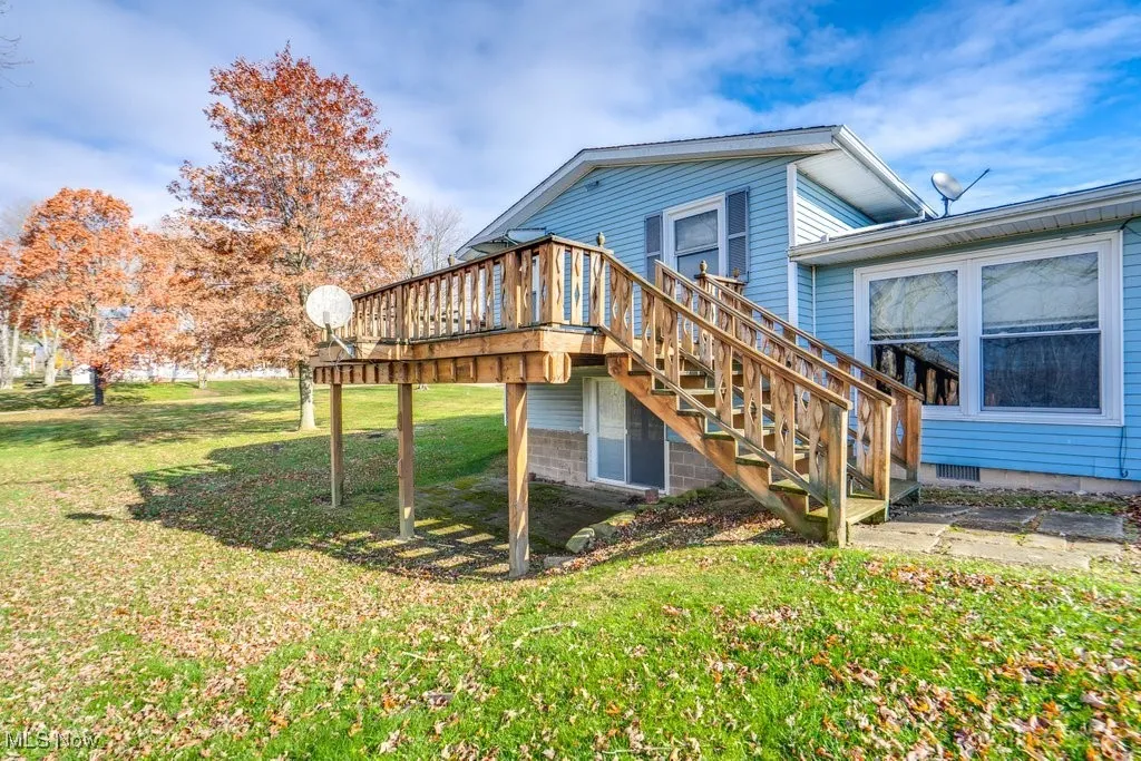 Rear view of house with a lawn, stairway, and a wooden deck